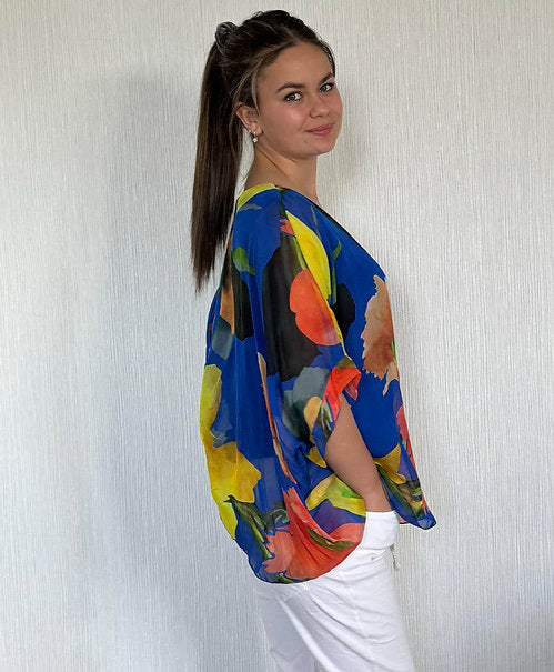 Woman wearing a colorful blouse with abstract patterns against a plain background