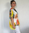 Woman wearing a colorful floral blouse against a plain background