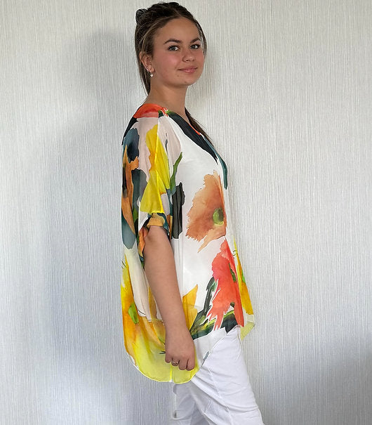 Woman wearing a colorful floral blouse against a plain background