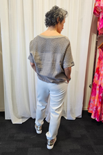 Person wearing a patterned top and white pants standing in front of a white curtain with a colorful dress on a rack to the side.
Italian Relaxed Lounge Pants White