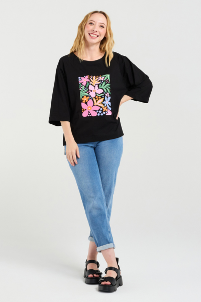 Woman wearing a black top with a colorful floral design and blue jeans on a white background
Kate T-Shirt Black