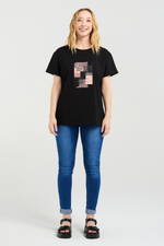 Woman wearing a black t-shirt with a graphic design and blue jeans on a white background
Livia T-Shirt Black