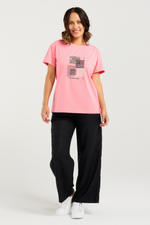 Woman wearing a pink t-shirt with a graphic design and black pants on a white background
Livia T-Shirt Pink