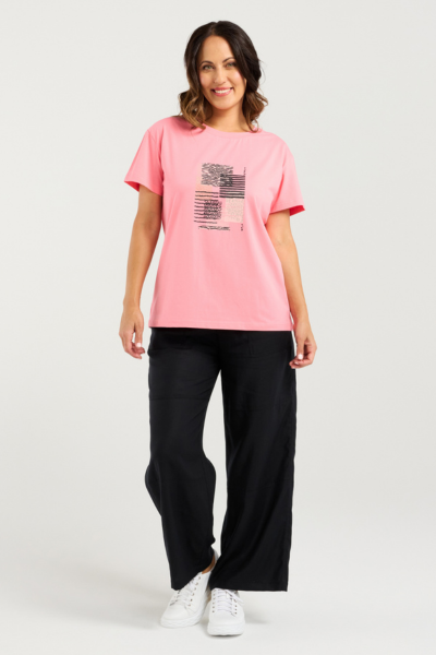 Woman wearing a pink t-shirt with a graphic design and black pants on a white background
Livia T-Shirt Pink
