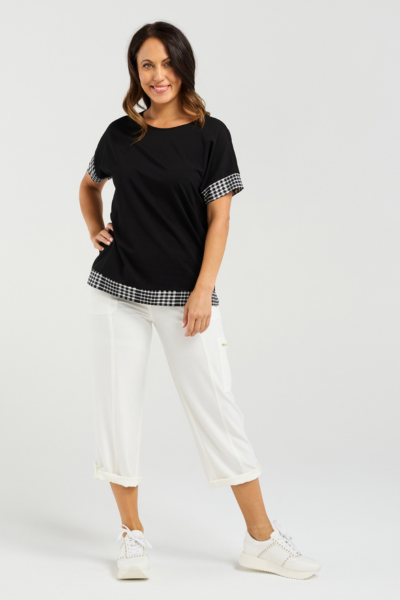 Woman wearing a black top with checkered sleeves and white pants on a white background Luna Top Black Check