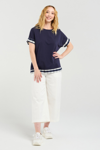 Woman wearing a navy blue top with white trim and white pants on a white background Luna Top Ink Check