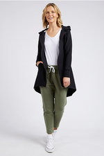 Woman wearing a black coat, white shirt, green pants, and white sneakers on a white background
Mara Zip Hoodie Black