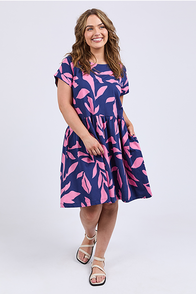 Woman wearing a navy dress with pink leaf pattern on a white background
Mimosa Dress Blue Depths