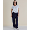 Woman wearing a white t-shirt and navy pants with white stripes on a beige background