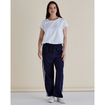 Woman wearing a white t-shirt and navy pants with white stripes on a beige background
