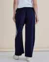 Navy blue pants with white stripes worn by a person on a beige background