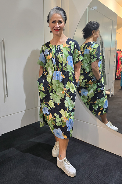 Woman wearing a floral dress standing in front of a mirror. Pleat Front Dress Black