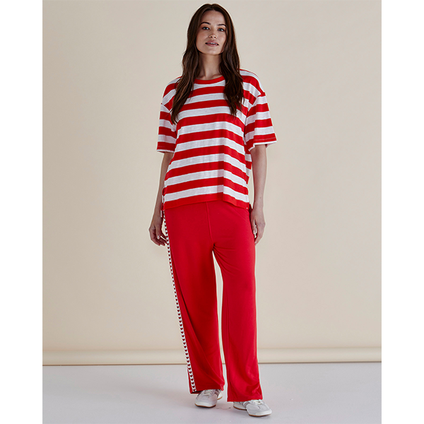 Woman wearing a red and white striped shirt and red pants against a beige background