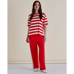 Woman wearing a red and white striped shirt and red pants against a beige background