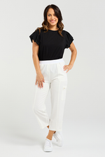 Woman wearing a black top and white pants on a plain background
Rhea Pants White