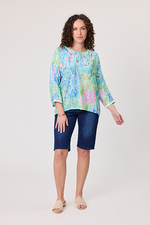 Woman wearing a colorful floral blouse and blue shorts on a white background Rimini Top Aqua