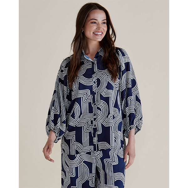 Woman wearing a navy and white patterned shirt dress on a plain background