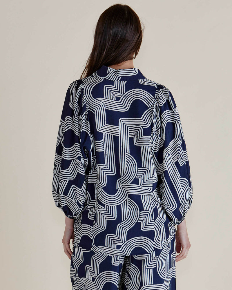 Person wearing a navy blue and white patterned shirt against a beige background