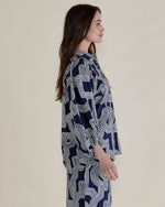 Woman wearing a navy blue patterned shirt against a plain background