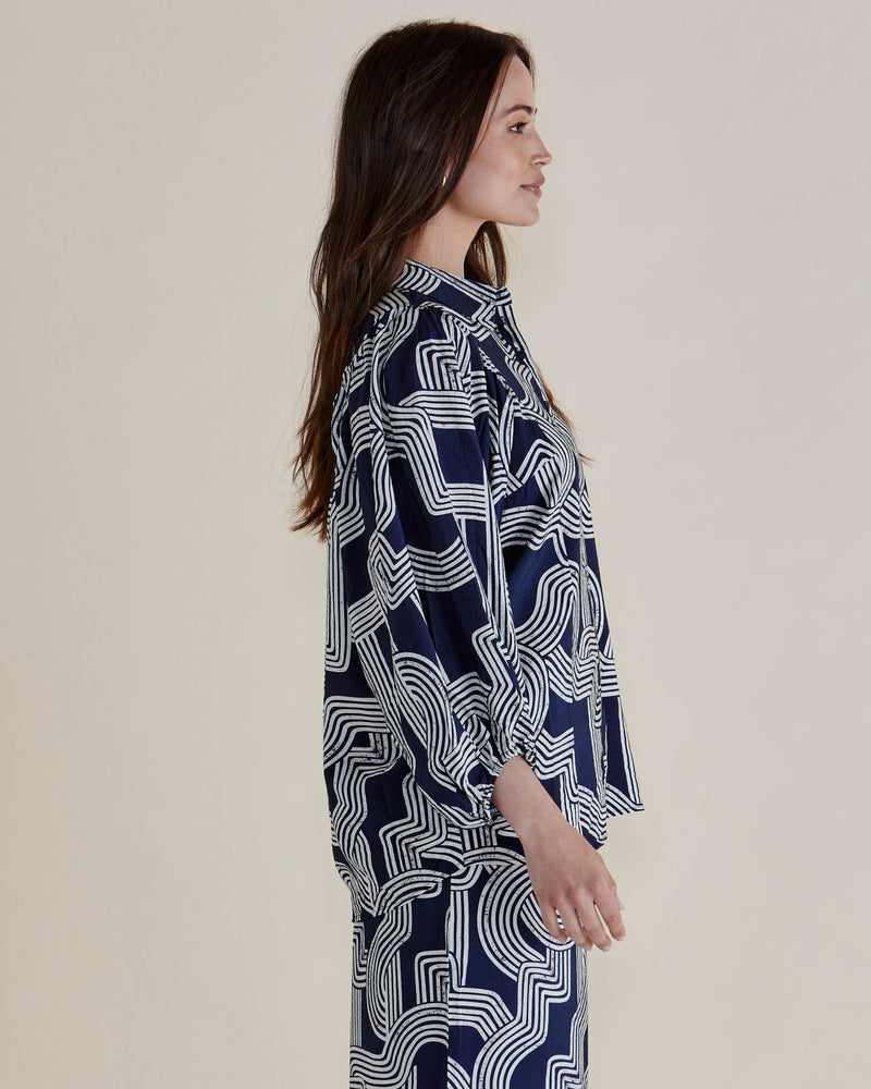 Woman wearing a navy blue patterned shirt against a plain background