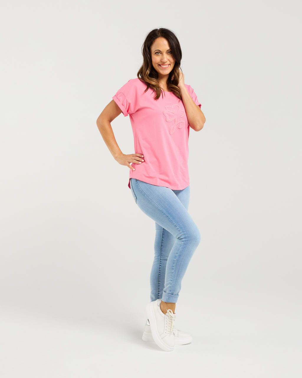 Woman wearing a pink t-shirt and light blue jeans on a white background Lily Top Pink