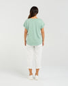 Person wearing a light green t-shirt and white pants on a plain background Lily Top Sage