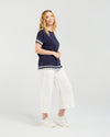 Woman wearing a navy blue top with white trim and white pants on a light gray background Luna Top Ink Check