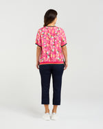 Woman wearing a pink floral top and navy pants on a white background Zoe Top Petal Confetti
