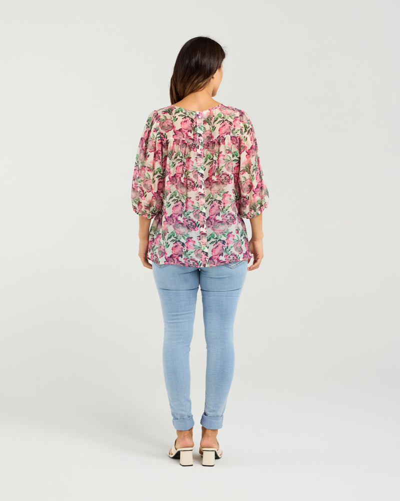 Woman wearing a floral blouse and light blue jeans on a white background
Ariel Top Rose Garden