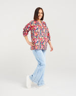 Woman wearing a colorful floral blouse and light blue jeans on a white background Evie Shirt Canvas Bloom