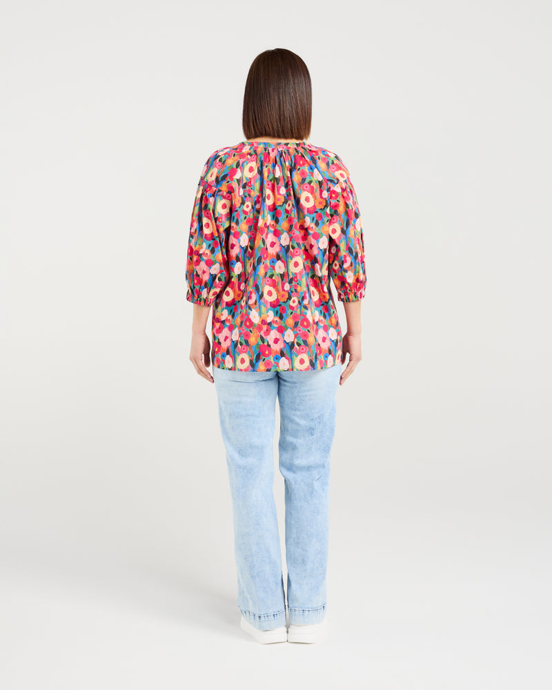 Woman wearing a colorful floral blouse and light blue jeans on a white background Evie Shirt Canvas Bloom