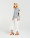Woman wearing a blue top and white pants on a plain background
Lilah Top Grey