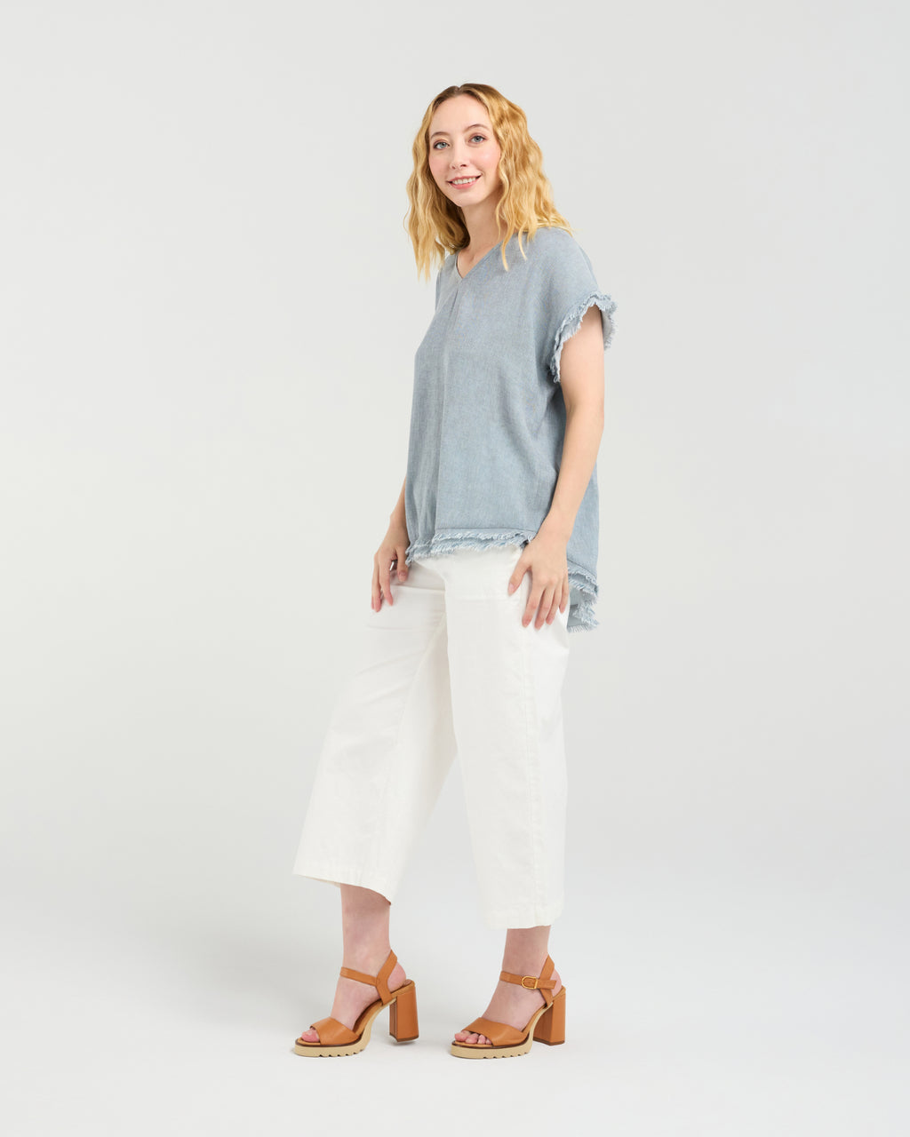 Woman wearing a blue top and white pants on a plain background
Lilah Top Grey