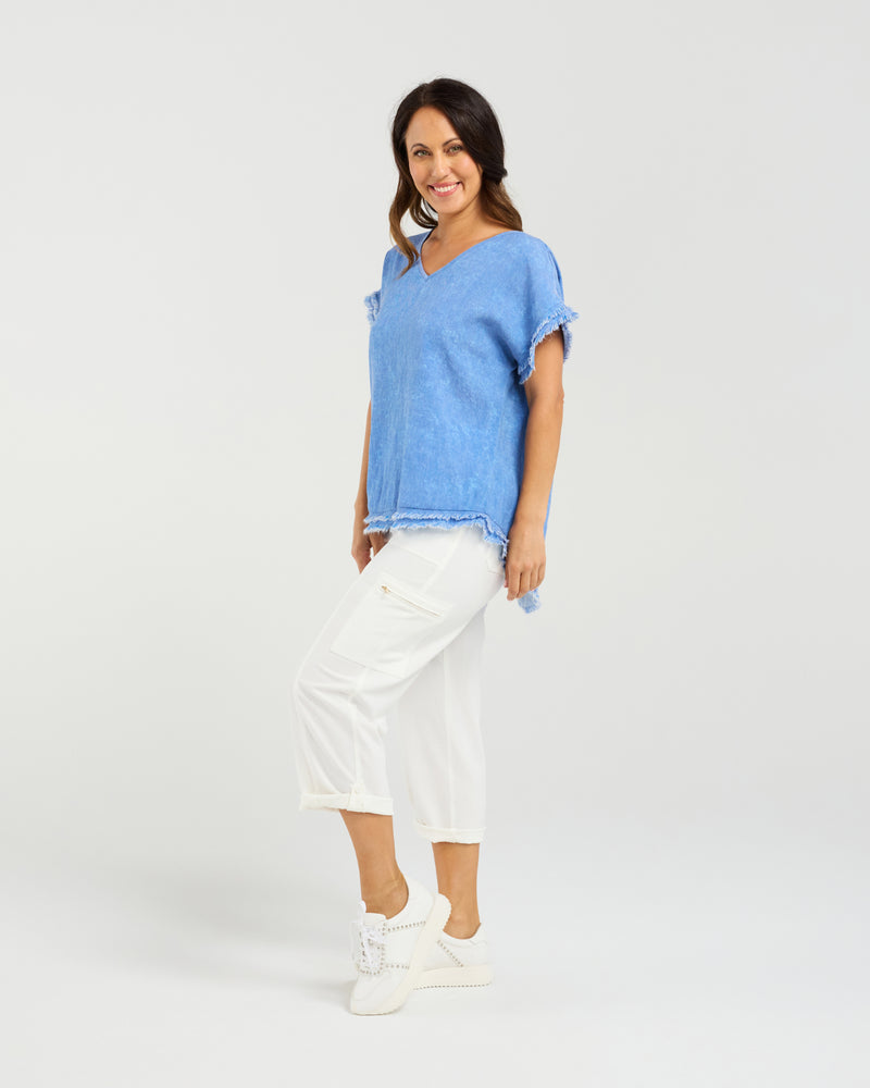 Woman wearing a blue top and white pants on a plain background
Lilah Top Blue