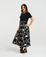 Woman wearing a black dress with white floral patterns on a white background
Delilah Dress Black Garden