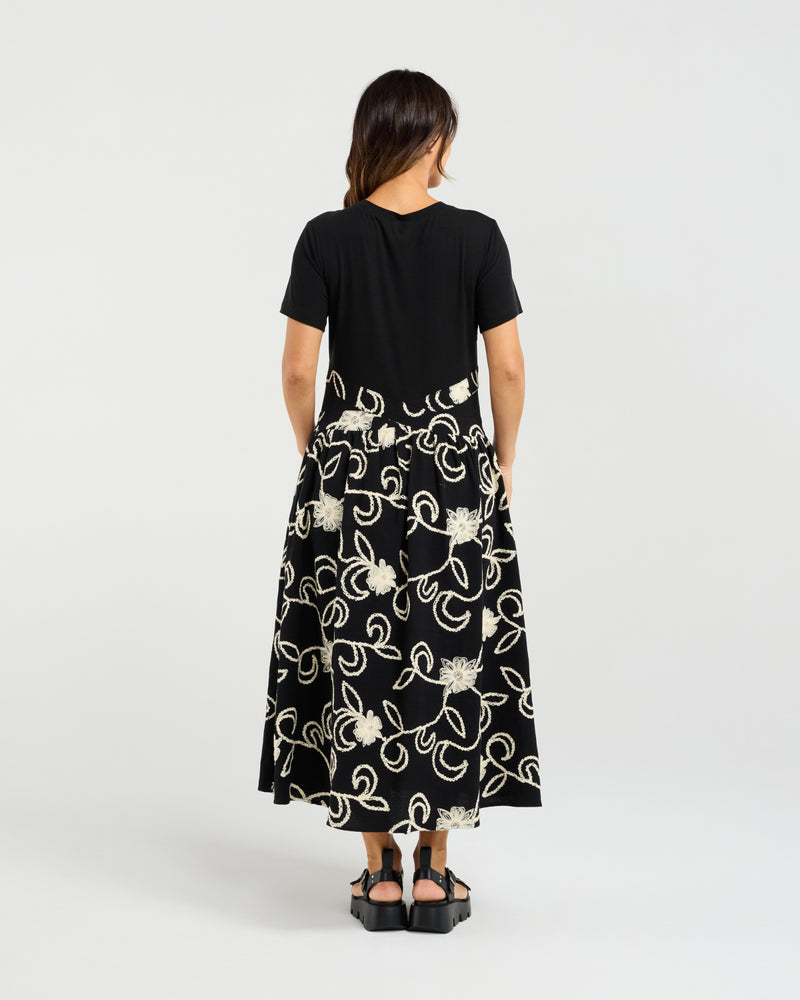 Woman wearing a black dress with white floral patterns on a white background
Delilah Dress Black Garden