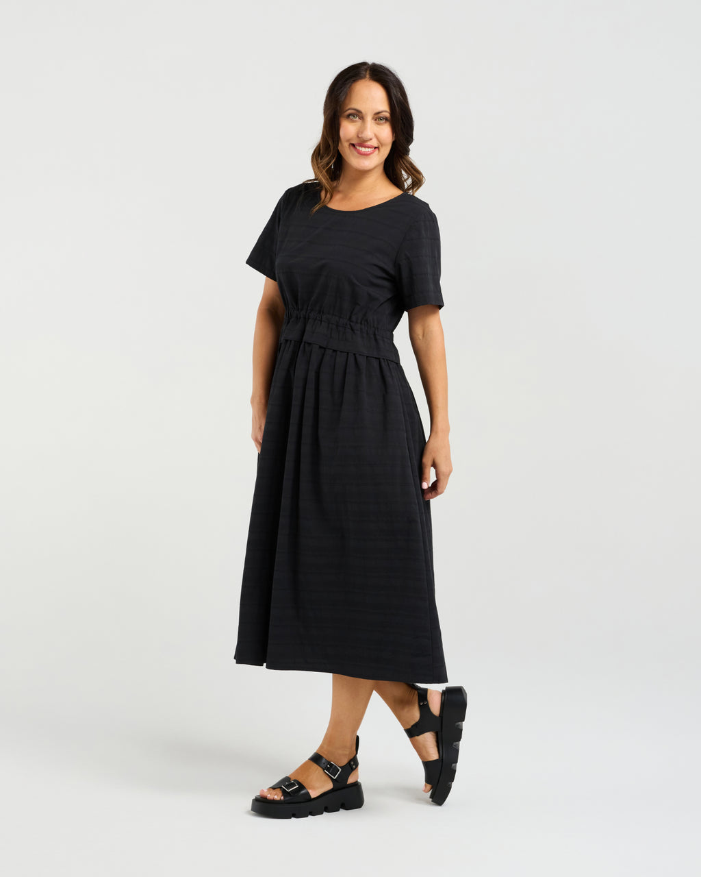 Woman wearing a black dress on a white background Brodie Dress Black