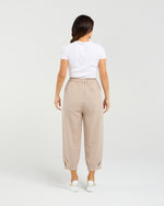 Woman wearing beige pants and a white shirt on a plain background Nova Pants Natural