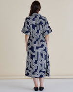 Woman wearing a navy and white patterned dress against a beige background