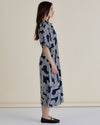 Woman wearing a navy patterned dress on a beige background