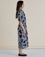 Woman wearing a navy patterned dress on a beige background