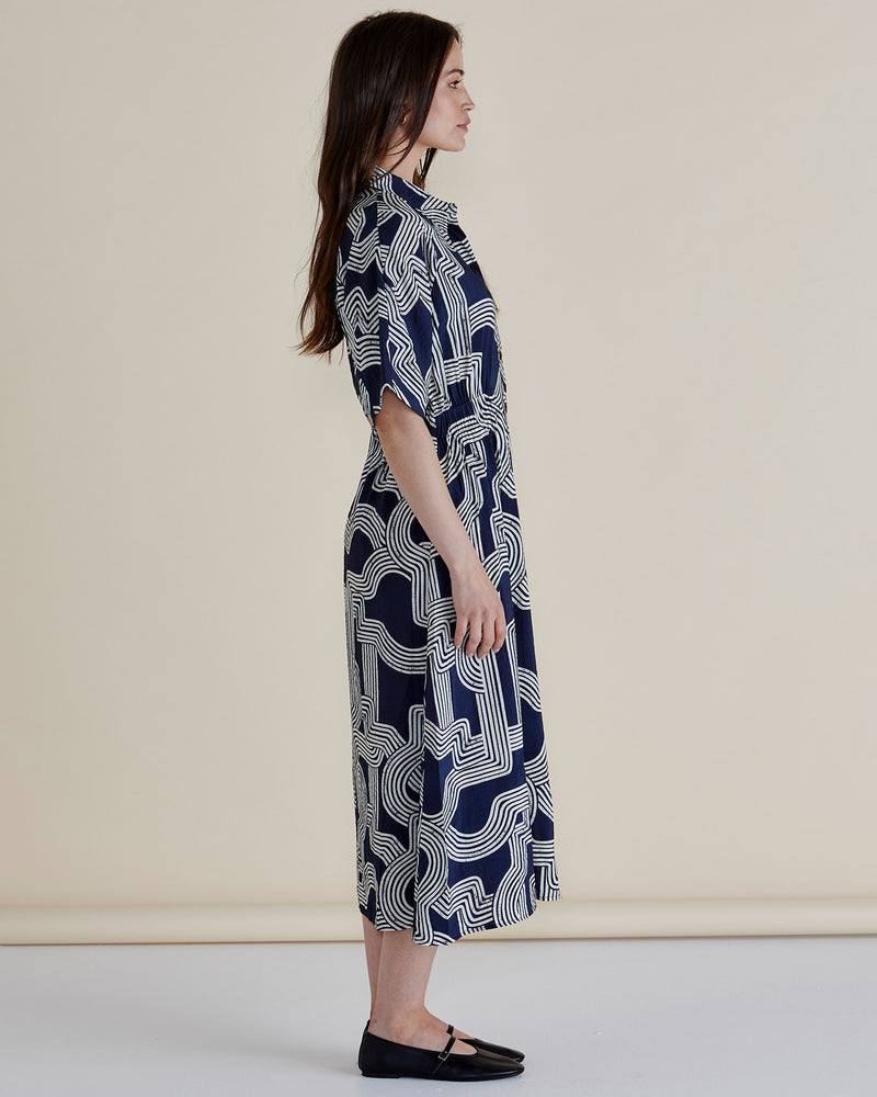 Woman wearing a navy patterned dress on a beige background