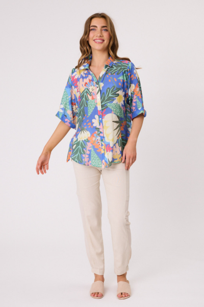 Woman wearing a colorful floral blouse and beige pants on a white background Sofia Printed Shirt Blue