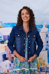 Woman wearing a denim jacket over a floral dress with a scenic background