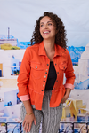 Woman wearing an orange jacket in front of a scenic backdrop
