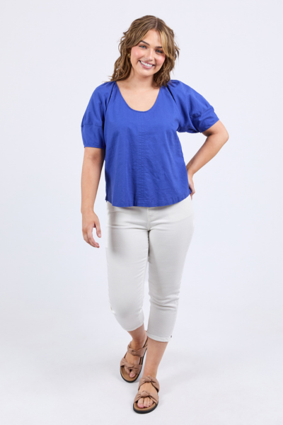 Woman wearing a blue top and white pants on a white background
The Grove Top Ocean Blue
