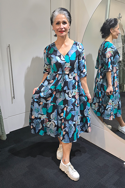 Woman wearing a floral dress standing in front of a mirror. Tie Front Dress Blue