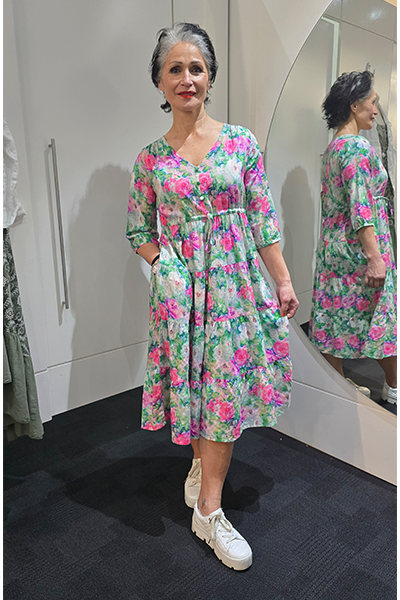Woman wearing a floral dress in a fitting room. Tie Front Dress Green