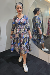 Woman wearing a patterned dress and white sneakers standing in front of a mirror. Tie Front Dress Multi