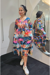 Woman wearing a colorful dress standing in front of a mirror. Tie Front Dress Turquoise